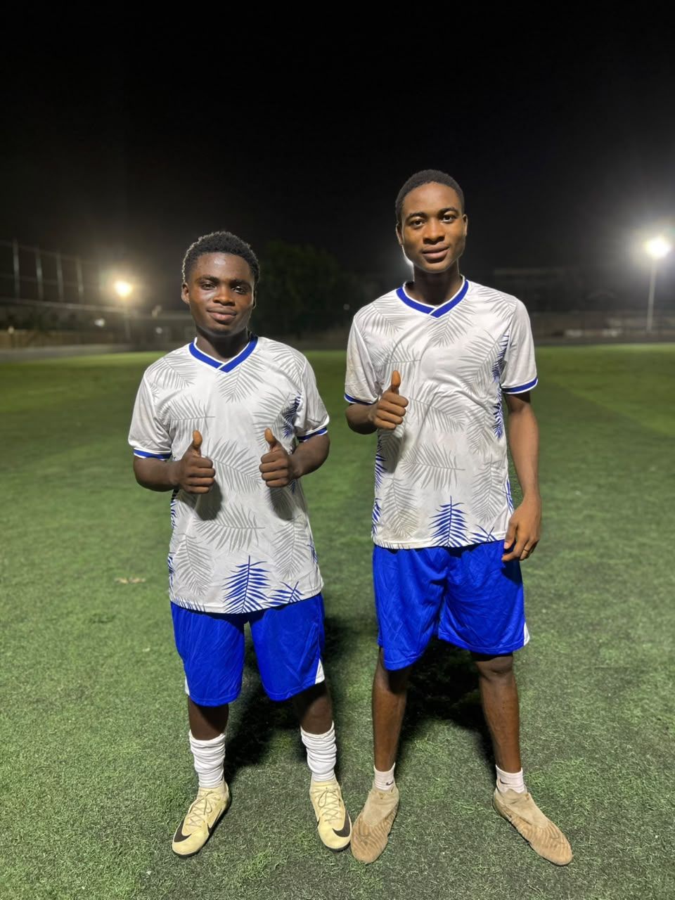 Two players under floodlights giving a thumbs up